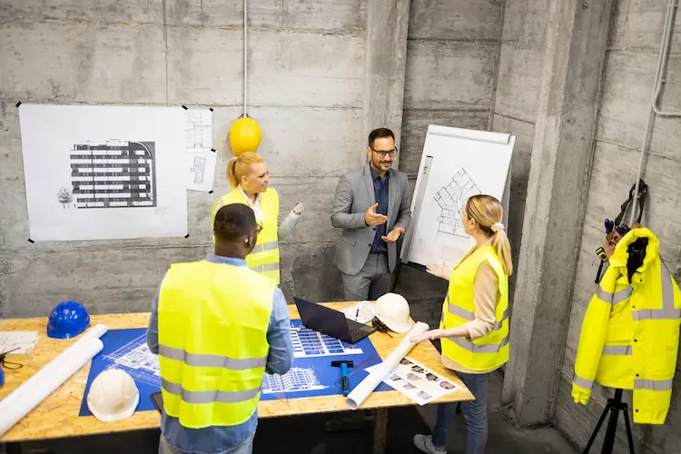 ingenieros y arquitectos reunidos en el sitio de construccion analizando la siguiente fase del edificio